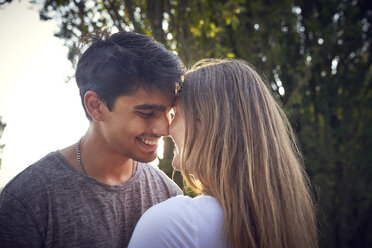 Glückliches junges Paar umarmt und küsst sich in einem Park im Sommer - SRYF00803