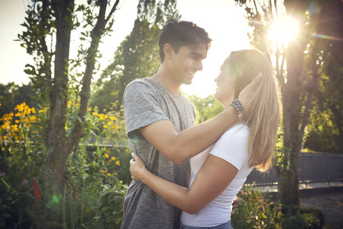 Glückliches junges Paar umarmt und küsst sich in einem Park im Sommer - SRYF00805