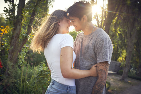 Glückliches junges Paar umarmt und küsst sich in einem Park im Sommer - SRYF00809