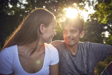 Romantic young couple sitting in park, enjoying sunset - SRYF00815