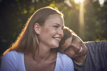 Romantic young couple sitting in park, enjoying sunset - SRYF00817