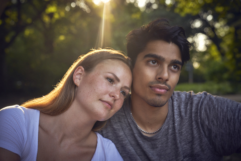 Romantisches junges Paar sitzt im Park und genießt den Sonnenuntergang, lizenzfreies Stockfoto