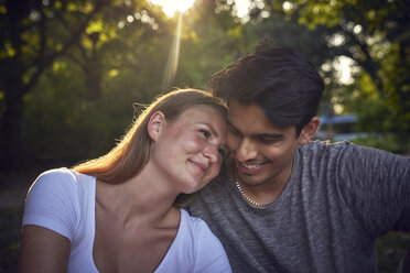 Romantic young couple sitting in park, enjoying sunset - SRYF00822