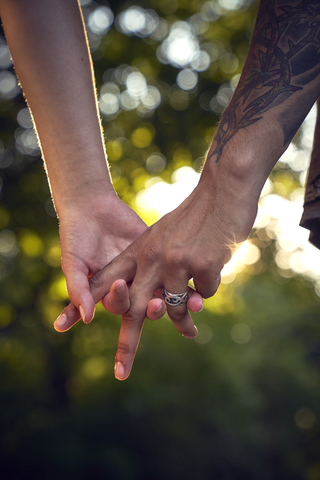 Ineinander verschlungene Hände eines jungen Paares, lizenzfreies Stockfoto