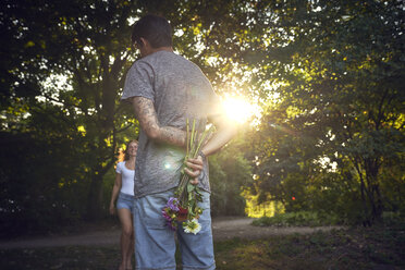 Junger Mann trifft seine Freundin in einem Park und schenkt ihr Blumen - SRYF00824