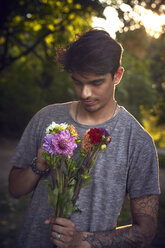 Junger Mann wartet mit einem Blumenstrauß - SRYF00828