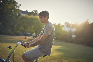 Young man riding bicycle in park - SRYF00843