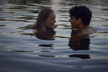 Romantisches Paar, das sich bei Sonnenuntergang im See umarmt - SRYF00855