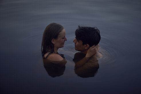 Romantisches Paar, das sich bei Sonnenuntergang im See umarmt - SRYF00859