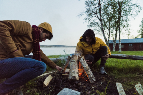 Schweden, Lappland, Zwei Freunde bereiten ein Lagerfeuer am Seeufer vor, lizenzfreies Stockfoto