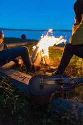 Freunde sitzen am Lagerfeuer und beobachten die Flammen - KKAF01932