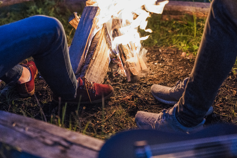 Freunde sitzen am Lagerfeuer und beobachten die Flammen, lizenzfreies Stockfoto