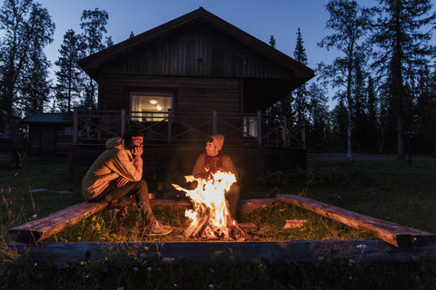 Freunde sitzen am Lagerfeuer und beobachten die Flammen, lizenzfreies Stockfoto