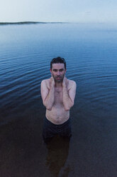 Mann mit nackter Brust steht im See und wäscht sich den Hals - KKAF01955