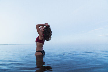 Woman wearing bikini, standing in water of a lake - KKAF01958