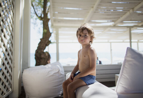 Porträt eines kleinen Jungen, der sich in einer Lounge am Strand ausruht - AZOF00033
