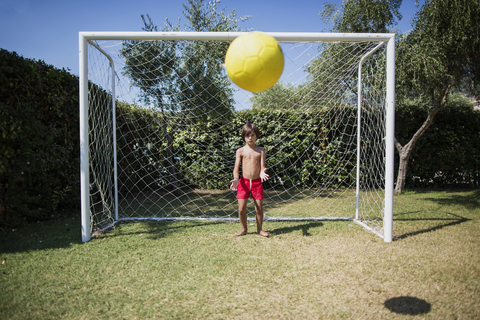 Little boy standing in front of soccer goal watching football stock photo
