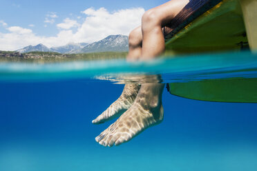 Füße eines Jungen, der auf einem im Wasser baumelnden Boot sitzt - AZOF00041