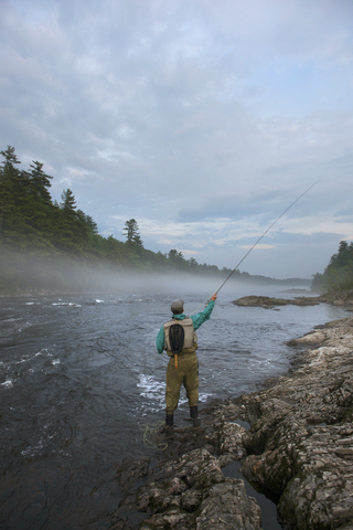 Fliegenfischer beim Werfen in die nebligen Gewässer des Kennebec River, Maine, lizenzfreies Stockfoto