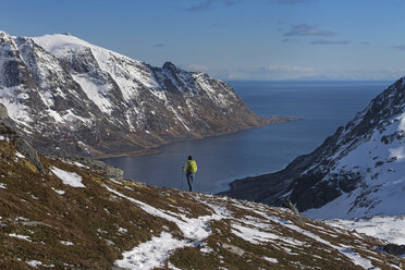 Female hiker descending rocky ridge towards Skjelfjord from Volandstind, Flakstad├©y, Lofoten Islands, Norway - AURF05052