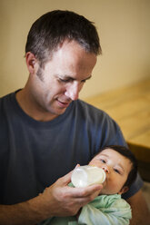 Father feeding daughter with bottle - AURF05065