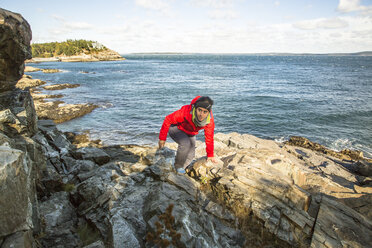 Hiker climbs around sea cliffs in Acadia National Park, Maine - AURF05166