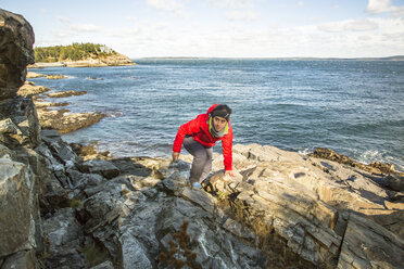 Wanderer klettert um die Meeresklippen im Acadia National Park, Maine - AURF05166