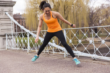 Happy Woman Doing Exercise Near The Railing Of The Bridge In The City - AURF05234