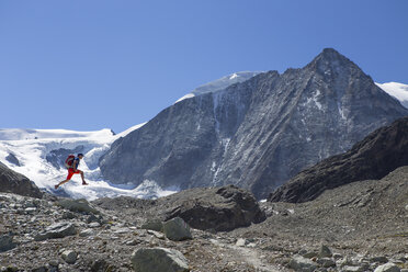 Männlicher Wanderer, der im Gebirge in die Luft springt - AURF05248