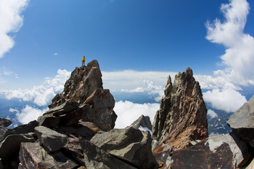 Man standing atop large jagged boulder while hiking, Lakes District, Chile - AURF05252