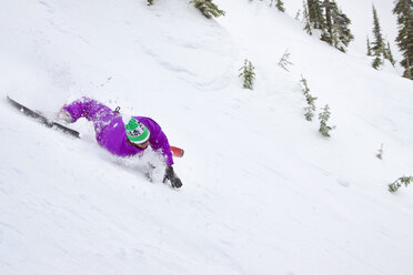 Männlicher Skifahrer fährt einen verschneiten Abhang hinunter - AURF05286