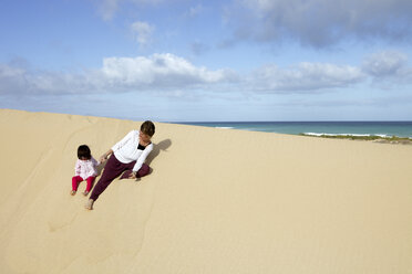 Mother playing with her daughter on a sand dune - AURF05337