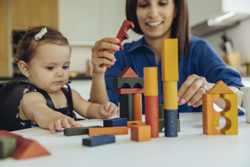 Happy mother and baby daughter playing with building blocks - MFF04656