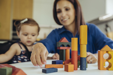 Glückliche Mutter und kleine Tochter spielen mit Bauklötzen, lizenzfreies Stockfoto