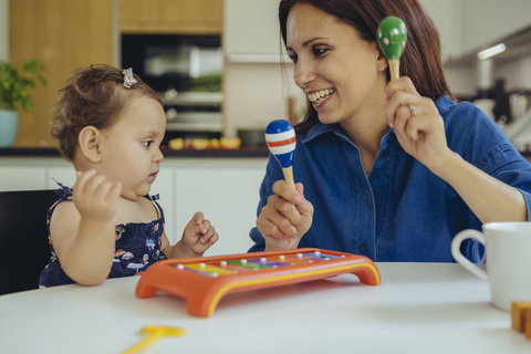 Happy mother and baby daughter playing with rattles stock photo