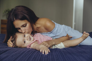 Mother kissing her baby girl on bed - MFF04661