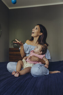 Happy mother playing with her baby girl on bed - MFF04666