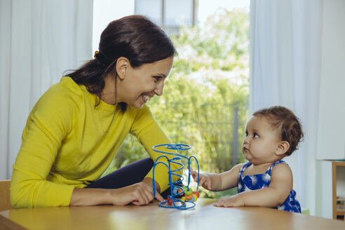 Happy mother and baby daughter playing with motoric loop - MFF04678