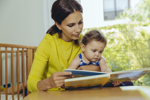 Mutter und kleine Tochter schauen sich ein Kinderbuch an - MFF04681