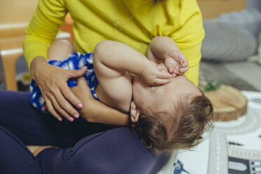 Müdes Baby, das sich auf dem Schoß der Mutter die Augen reibt - MFF04686