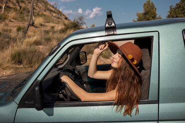 Smiling young woman wearing a hat sitting in a car - AFVF01560