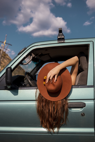 Woman wearing a hat leaning out of car window stock photo