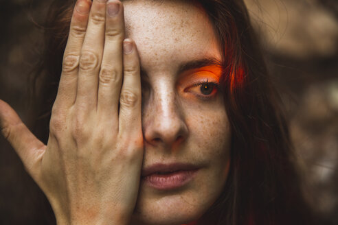 Porträt einer jungen Frau mit Sommersprossen, die ein Auge bedecken - AFVF01577