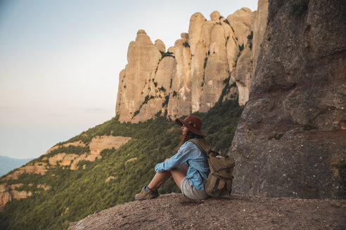 Junge Frau auf Wanderschaft mit Hut auf einem Felsen sitzend - AFVF01580