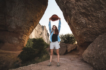 Happy young woman on a hiking trip holding a hat - AFVF01583