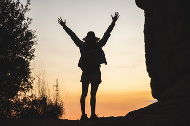 Rear view of woman on a hiking trip raising her arms at sunset - AFVF01585