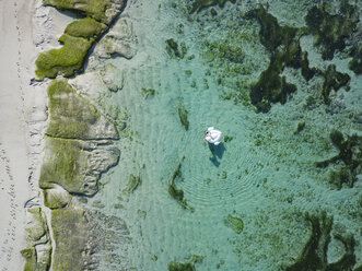 Indonesien, Bali, Luftaufnahme des Strandes Karma Kandara, eine Frau, Luftmatratze schwimmt auf dem Wasser - KNTF01668