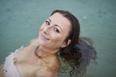 Porträt einer lächelnden jungen Frau beim Baden im See an einem regnerischen Tag - PNEF00884