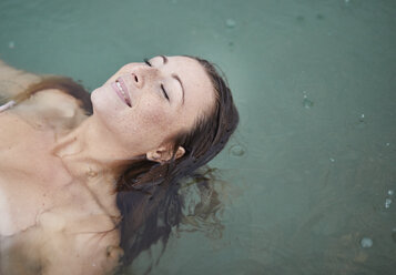 Porträt einer entspannten jungen Frau beim Baden im See an einem regnerischen Tag - PNEF00885