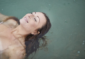 Portrait of relaxed young woman bathing in lake on rainy day - PNEF00885